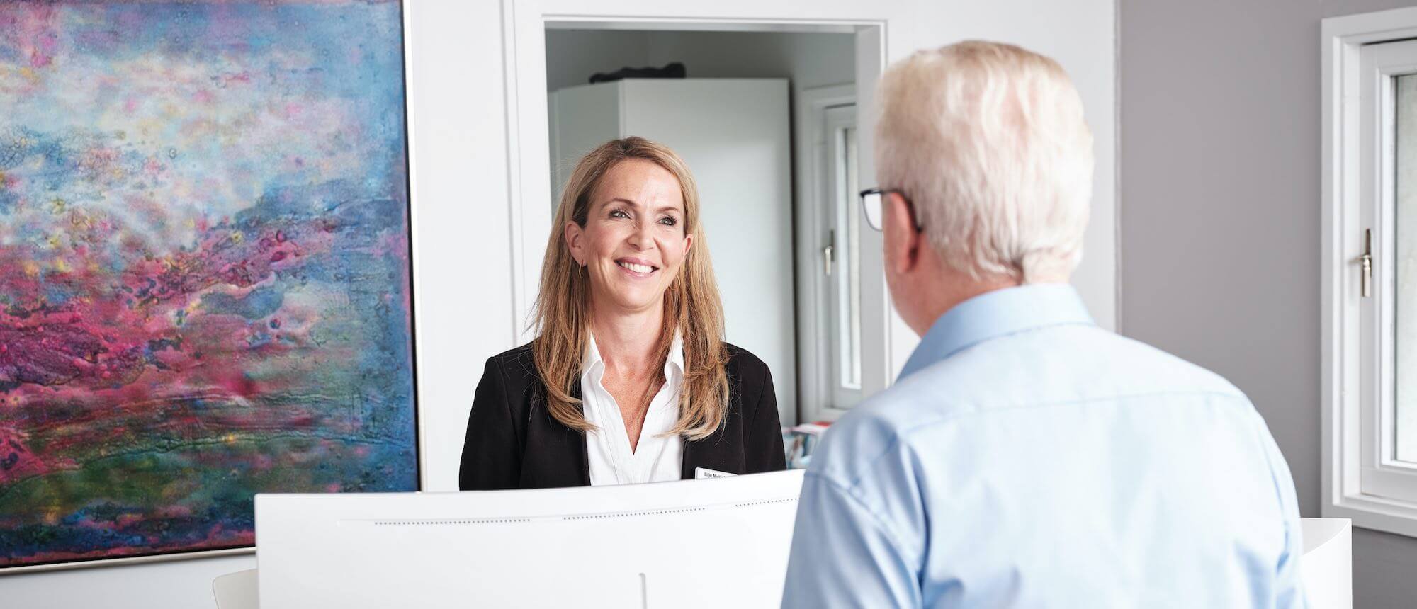 En patient med alderssyn bliver taget imod med et smil.