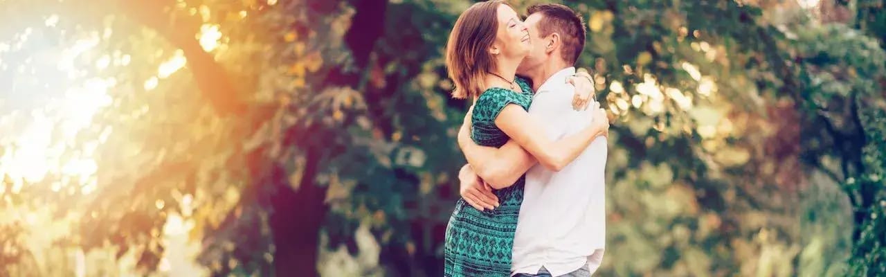 Et ung par, som giver hinanden et knus i en park.