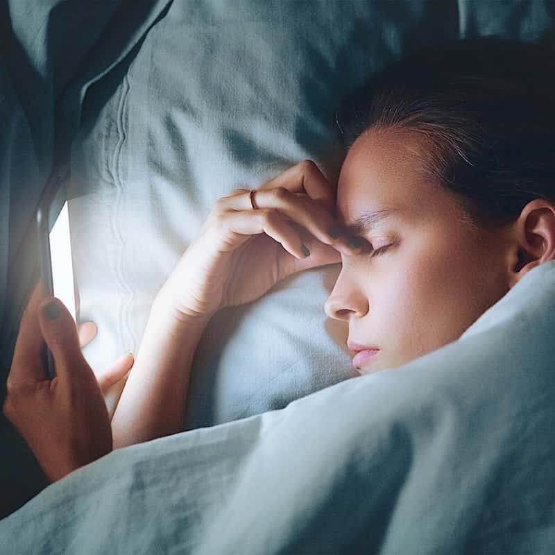 en dame oplever tørre og irriterede øjne ved brug af mobiltelefon