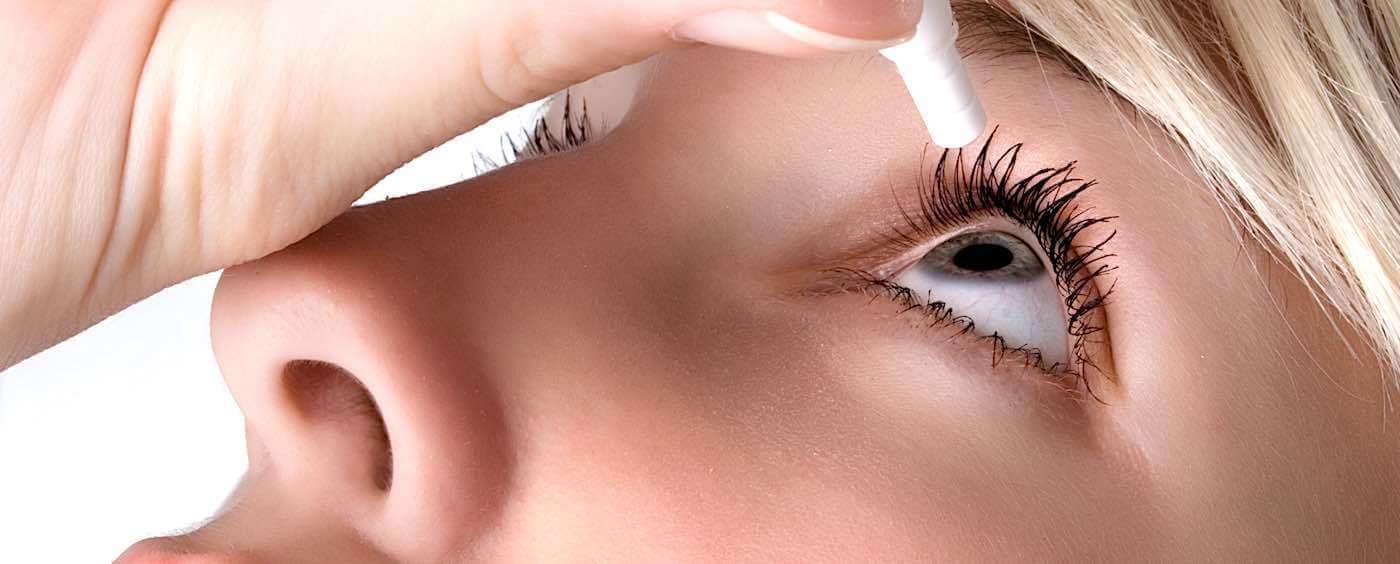 Billedet viser en person, som drypper sine øjne med øjendråber.