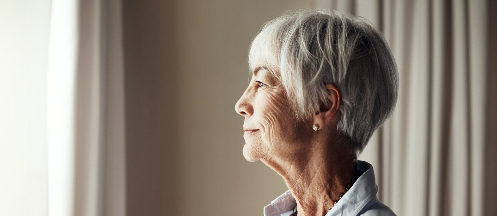 En ældre dame kigger ud af vinduet.