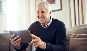 Nærafstand syn - læseafstand med tablet ipad. En mand sidder og læser en bog.